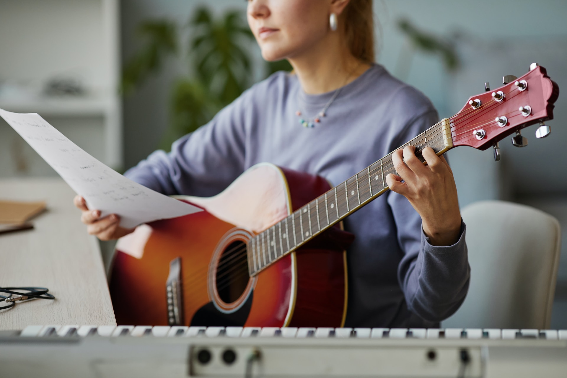 Une femme devant une partition chante en jouant de la guitare.