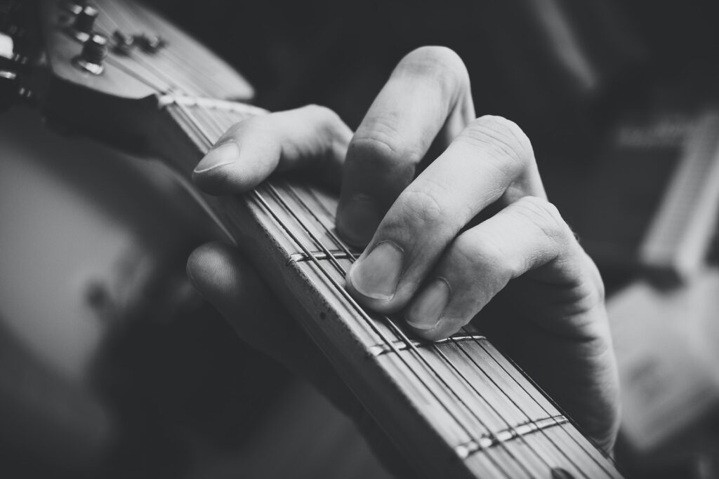 Un guitariste effectue un accord barré sur son manche de guitare.