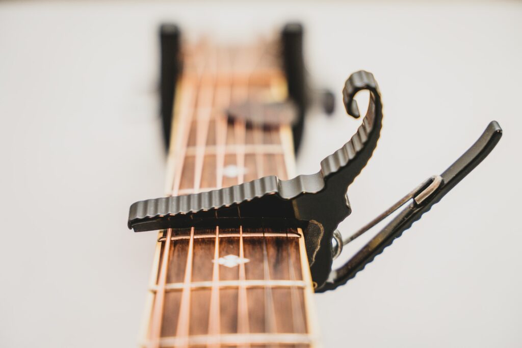 Un manche de guitare avec un capo appuyé sur les cordes.