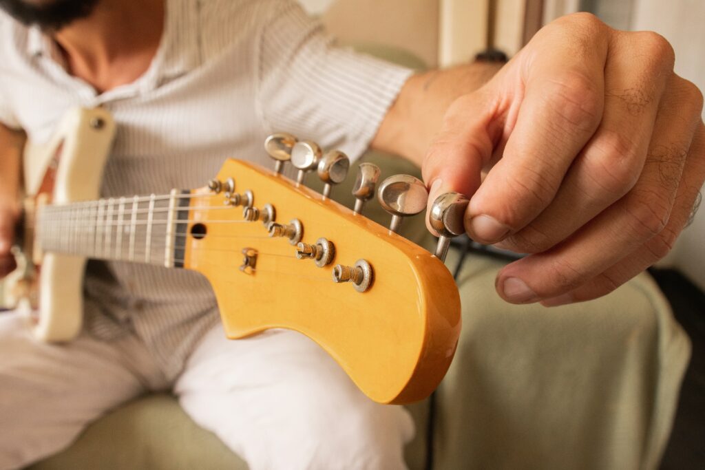 Un guitariste ajuste sa corde de Mi.