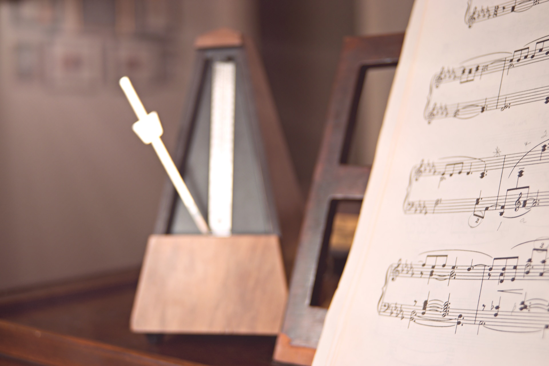 Un métronome posé sur un instrument en bois à côté d'une partition de piano.