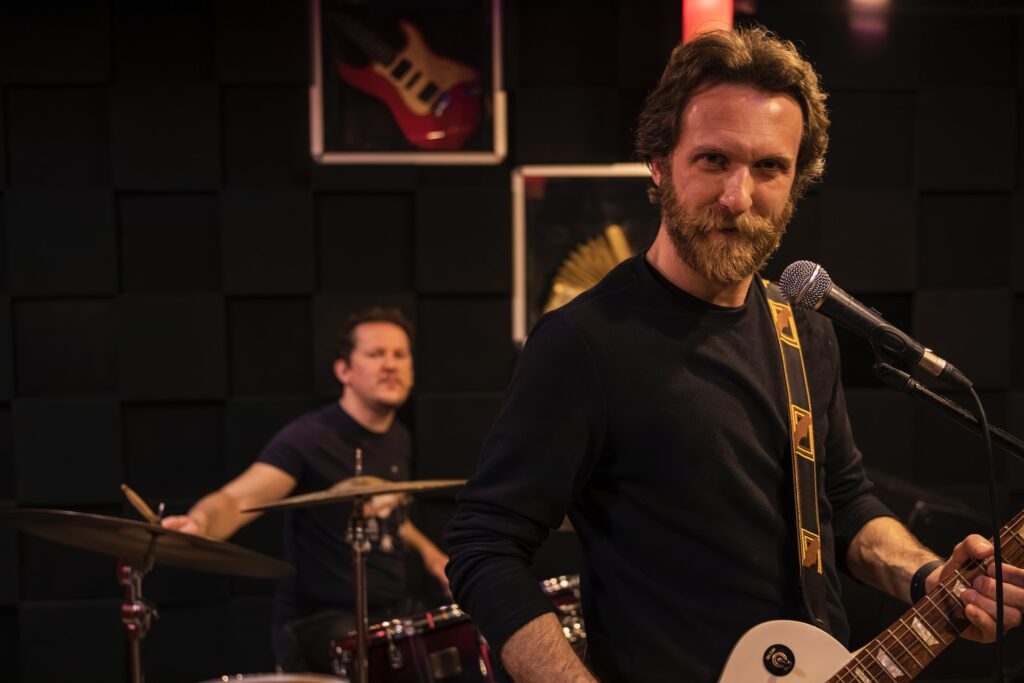 Un guitariste devant un batteur lors d'un concert sur scène.