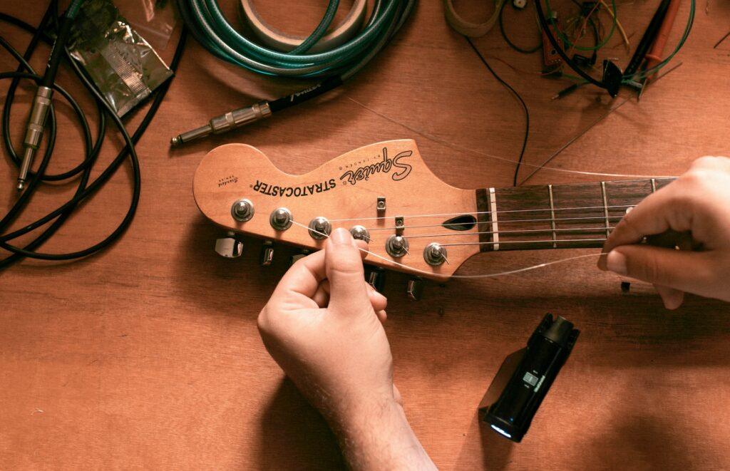 Une personne remplace les cordes de sa guitare.