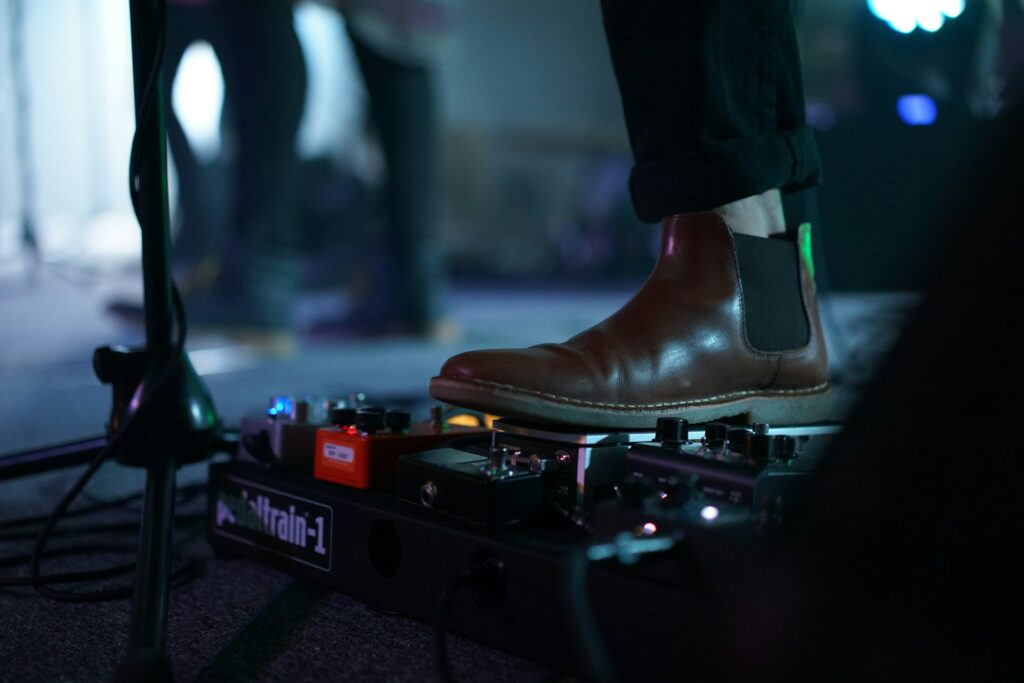 Un musicien avec des chaussures noires appuie sur des boutons pour modifier sa musique.