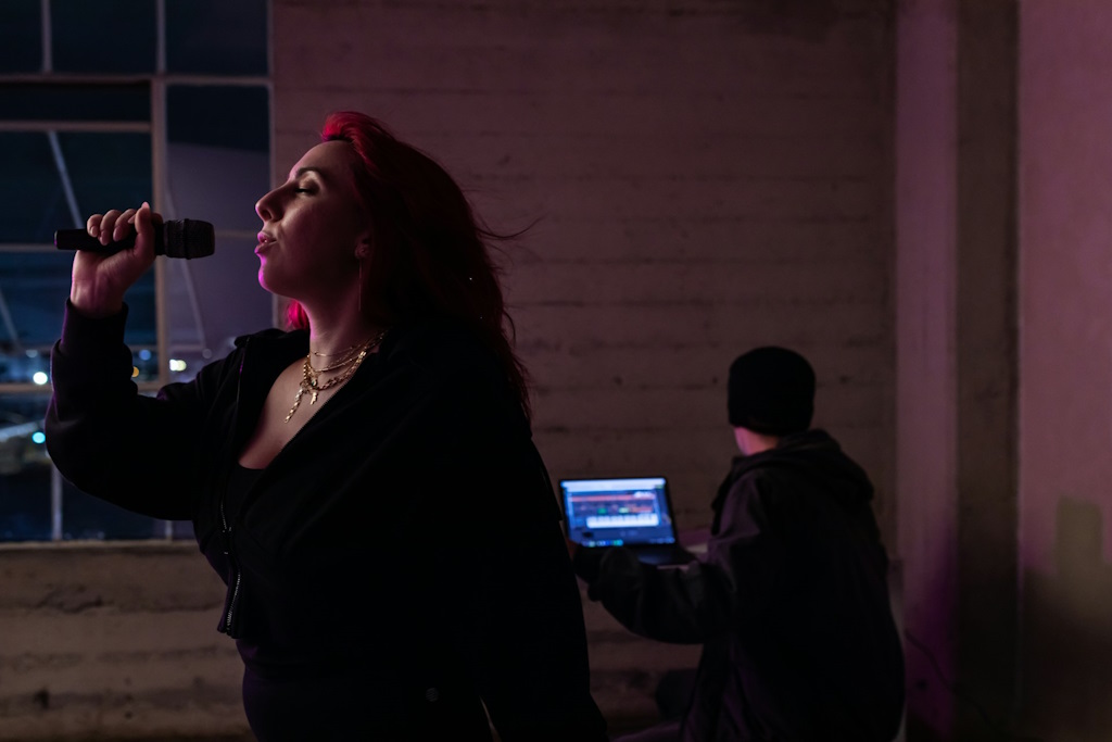 Une femme chante avec un micro devant un ordinateur.