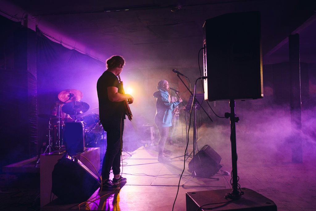 Un groupe de musique lors d'un spectacle sur scène, avec des lumières violettes.