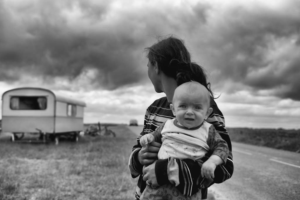 Une mère avec son enfant devant leur caravane en campagne.