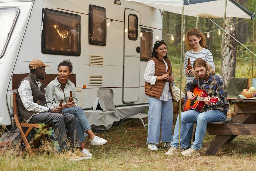 Des jeunes sous le auvent d'un camping-car.