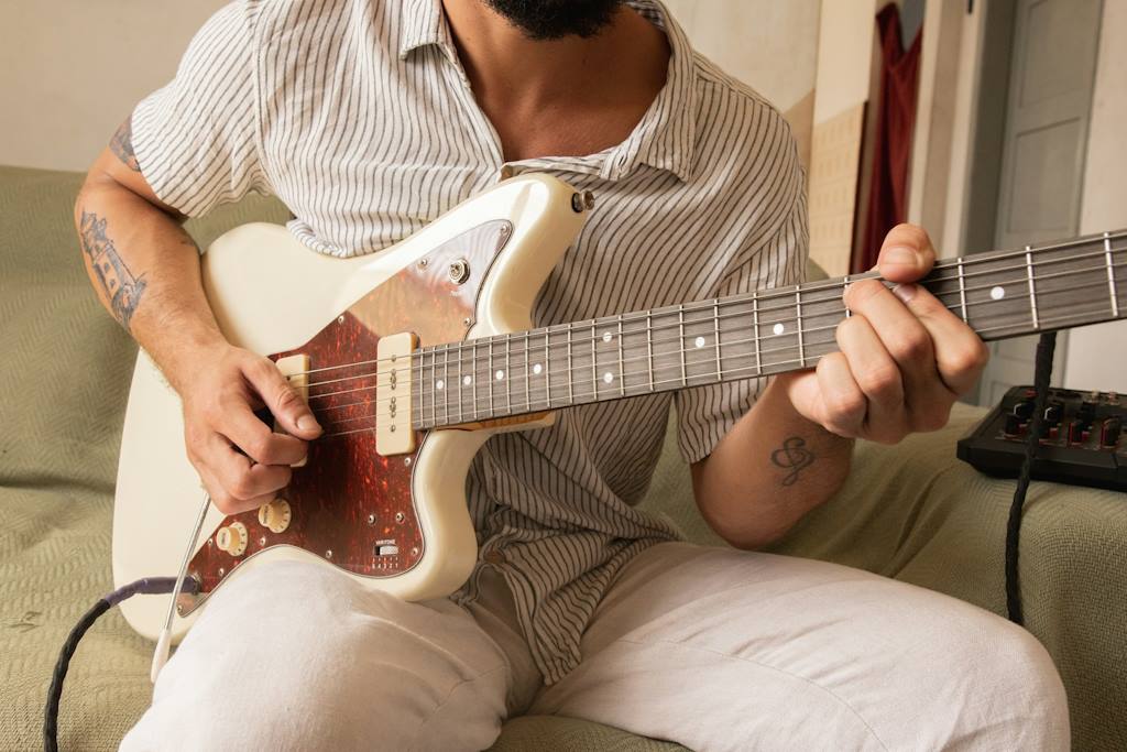 Un guitariste assis joue un accord.
