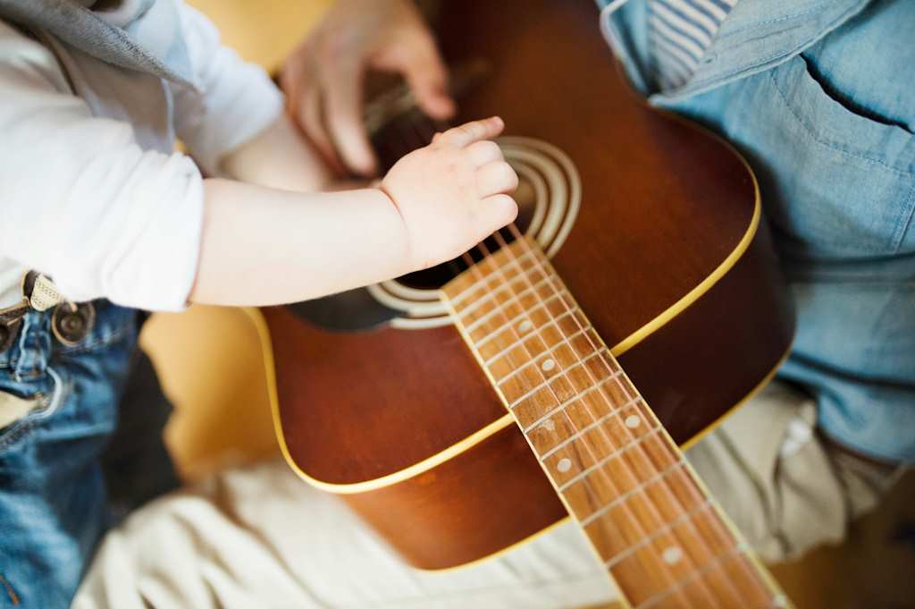 Les doigts d'un nouveau-né jouent sur des cordes de guitare.