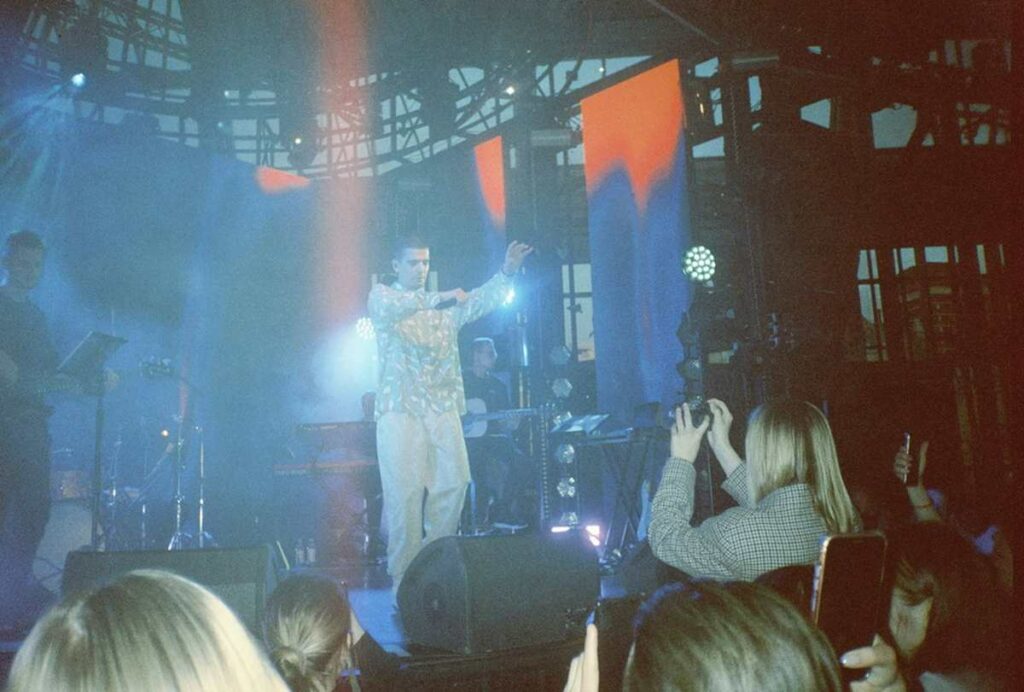 Un musicien se tient debout sur la scène, devant son public.