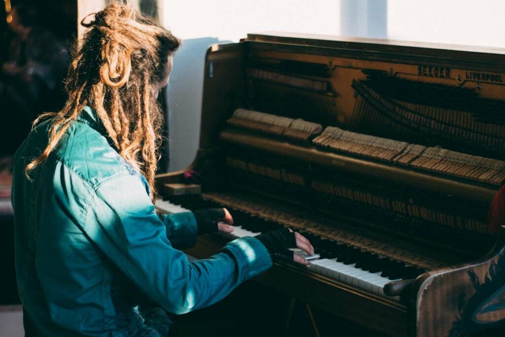 Une personne aux cheveux long joue du piano avec ses deux mains.