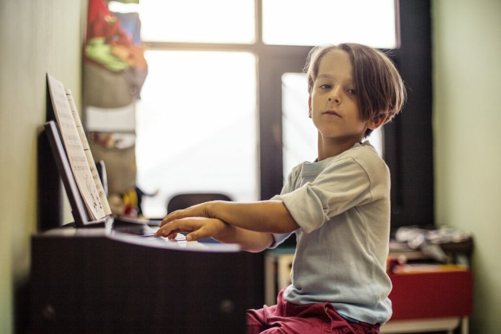 Un petit pianiste joue sans regarder la partition et en croisant les mains.