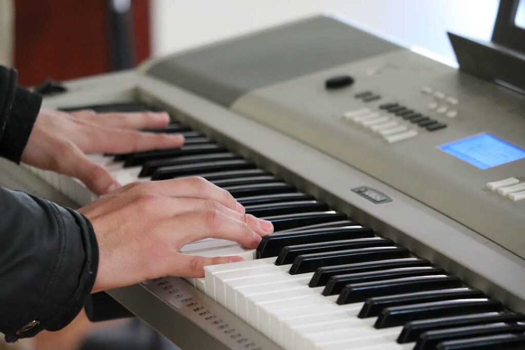 Deux mains sur l'octave grave d'un piano numérique.