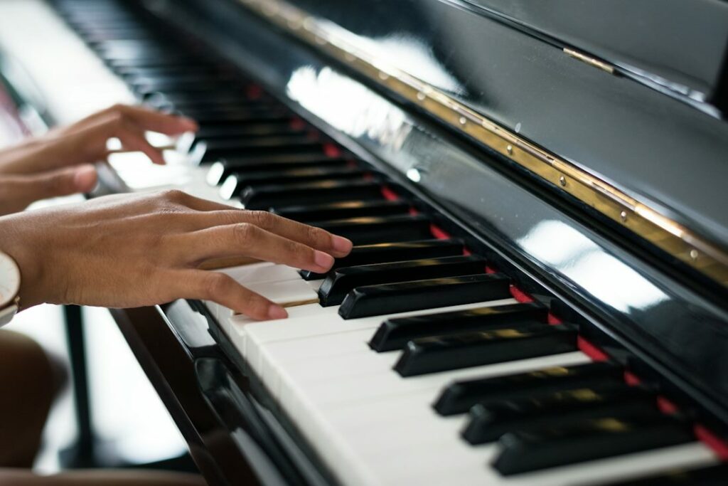 Vue rapprochée sur les mains d'une personne en train de jouer du piano.