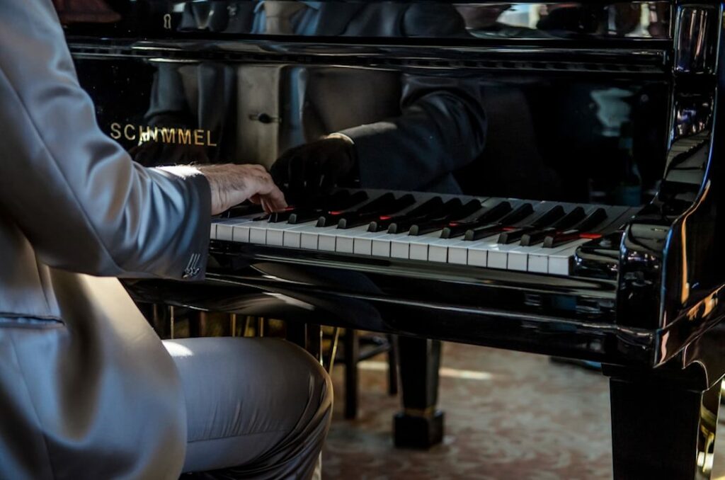 Un pianiste vue de dos en veste classe, photographié en train de jouer un morceau.