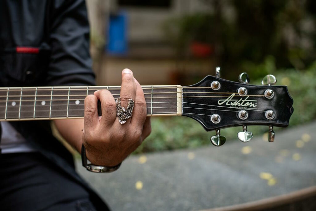 Vue rapprochée sur les doigts d'un guitariste en train de faire un accord barré.