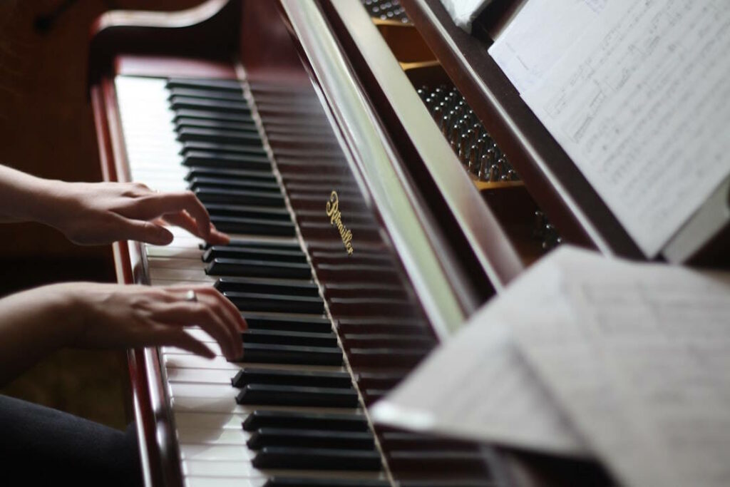 Vue sur les touches de piano avec les mains d'un pianiste en train de jouer un morceau.