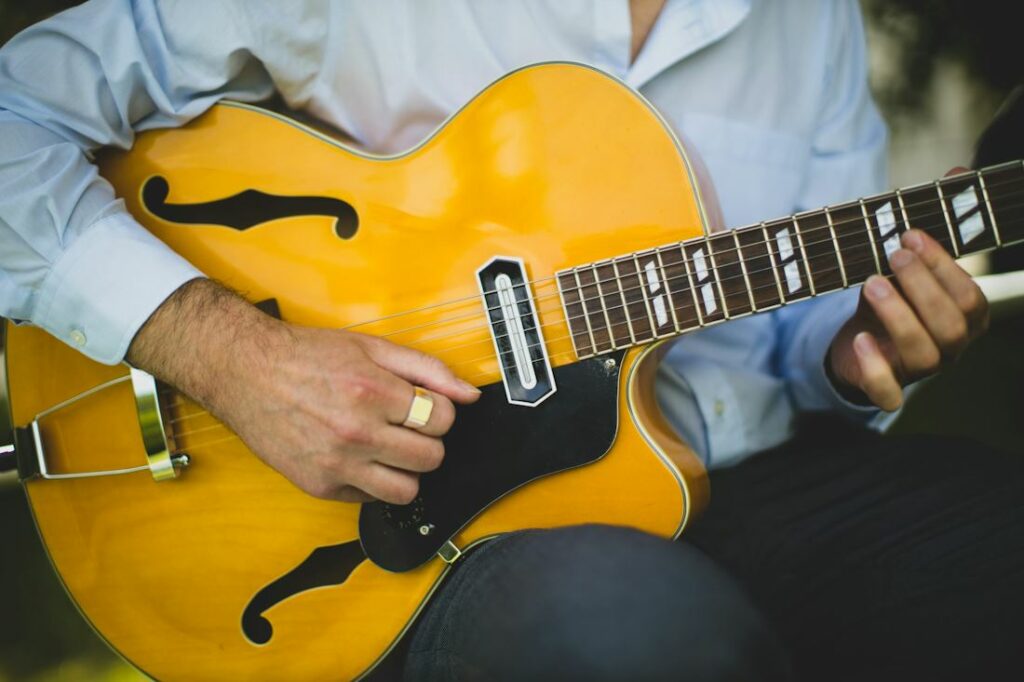 Vue rapprochée sur les bras d'un guitariste jouant un instrument de jazz.