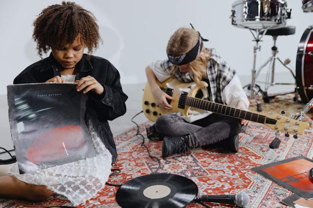 Une fille ouvre un disque vinyle et un garçon gratte les cordes de sa guitare.