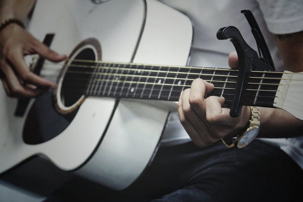 Vue rapprochée d'un homme jouant sur les cordes d'une guitare acoustique.