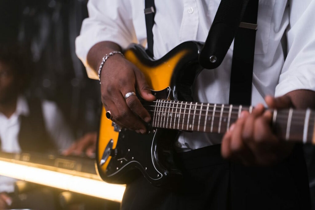 Vue rapprochée sur la guitare électrique d'un guitariste portant une chemise blanche.