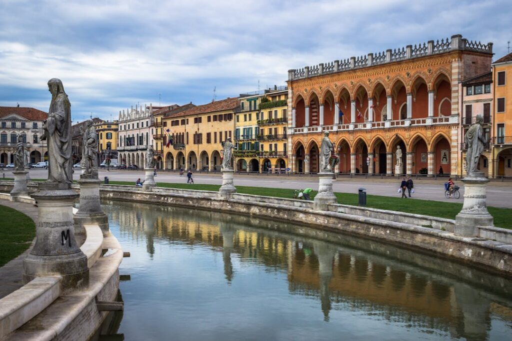 Des bâtiments colorés d'une ville italienne avec un cours d'eau et des statuettes.