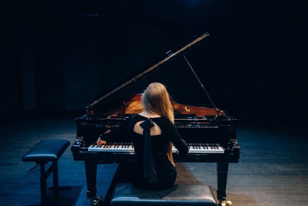 Vue de dos d'une pianiste en train de jouer sur un piano à queue lors d'un spectacle.