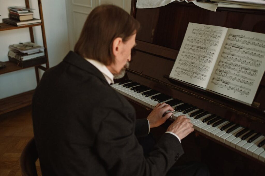 Un pianiste assez vieux aux cheveux long déchiffre un morceau de piano.