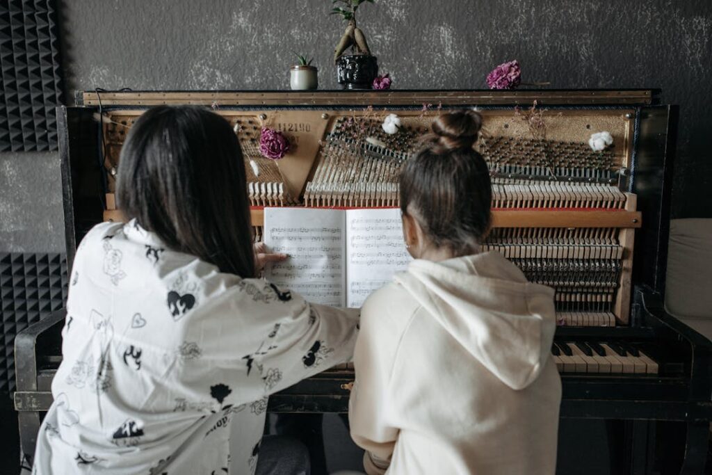 Deux femmes vues de dos, travaillent sur un piano.