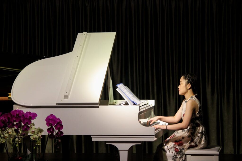 Une femme pianiste vue de profil lors d'un concert sur un piano blanc.