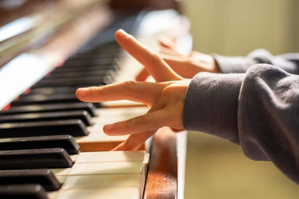 Les doigts d'un enfant qui joue un morceau de piano.