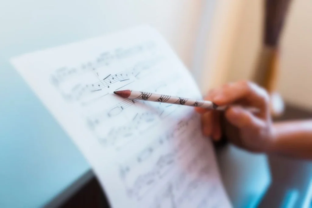 Une personne suit la lecture d'une portée de piano avec un crayon.