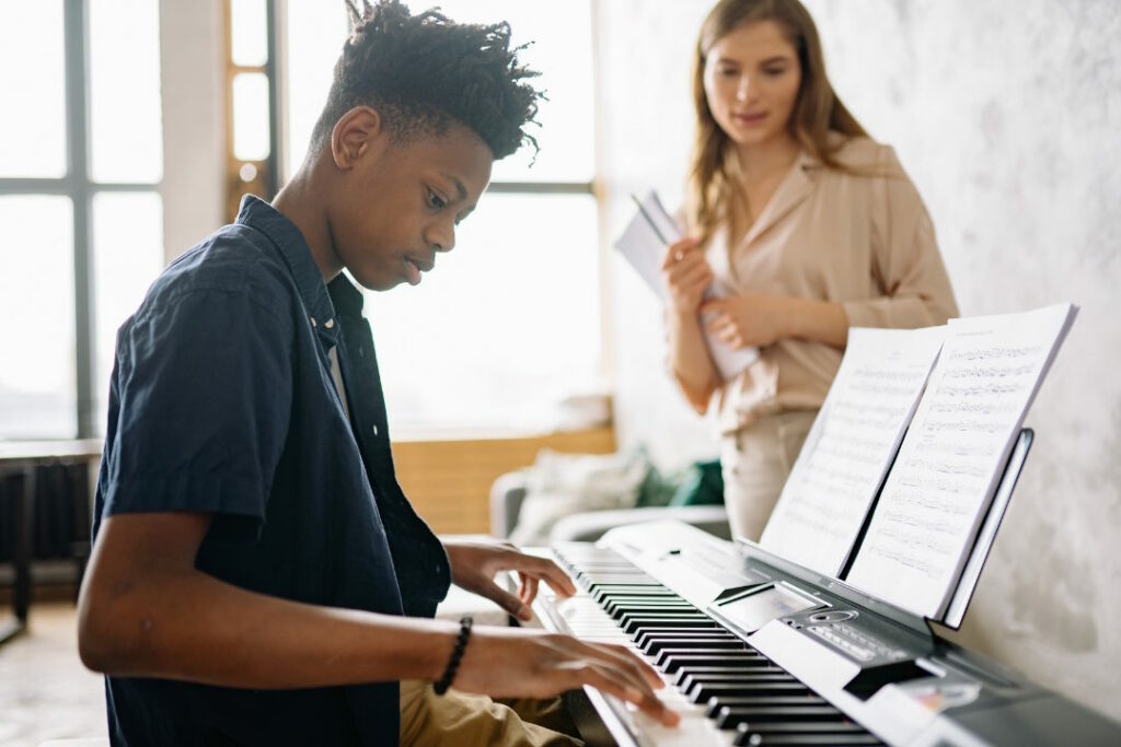 Un jeune homme joue au piano lors d'une leçon de musique.