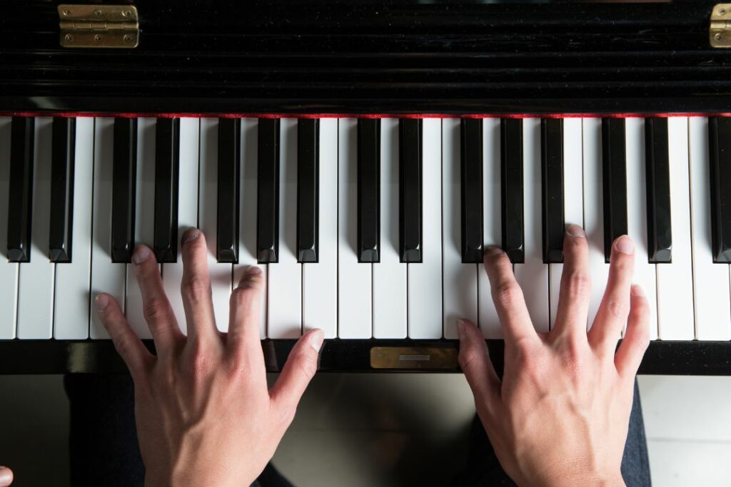 Deux mains en train de jouer un morceau de piano.