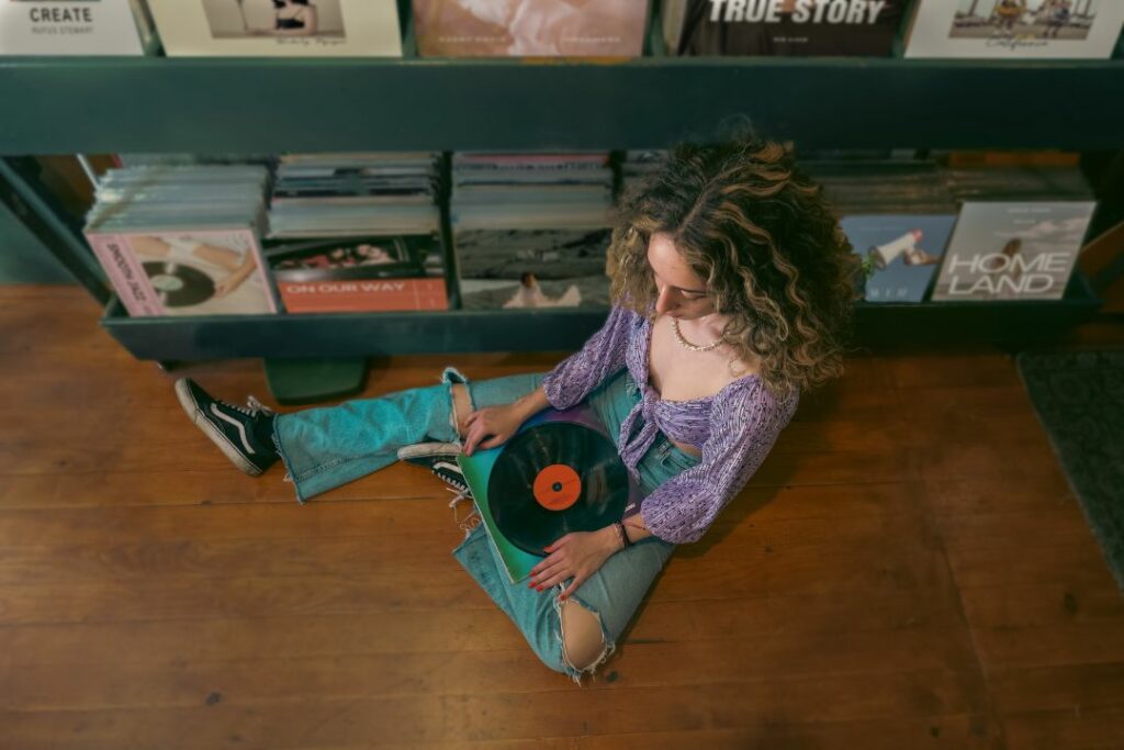 Une femme en train d'écouter un vinyle assise par terre.