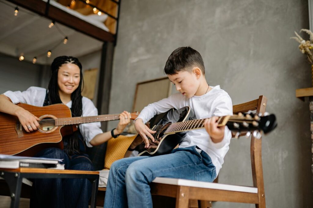 Un garçon en train de prendre un cours particulier de guitare.