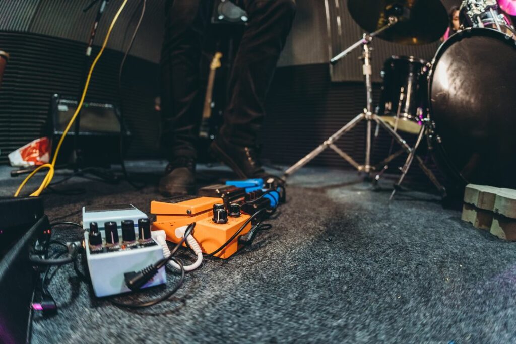 Des accessoires de guitare posés au sol, près d'une batterie.