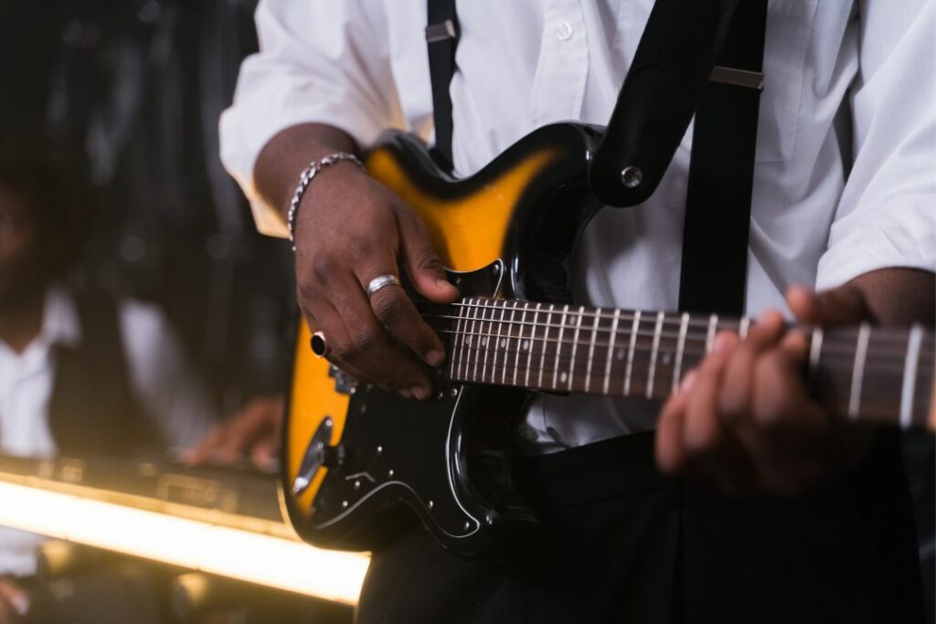 Vue rapproché sur un guitariste en train de plaquer un accord septième.