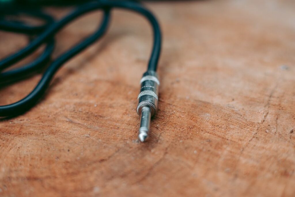 Connecteur jack 6,35 mm mono avec fiche métallique et câble noir sur table en bois