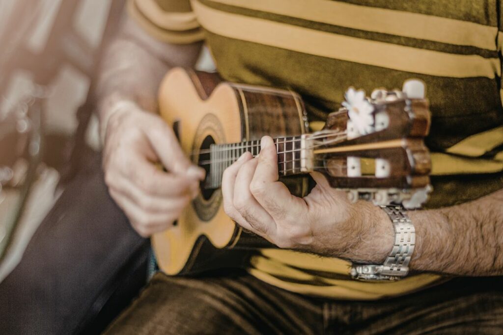 Gros plan sur une main plaquant un accord sur le manche d'un ukulélé en bois.